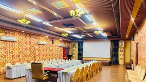 Ein Konferenzraum mit einem langen Tisch, Stühlen und einer Projektionsleinwand.
