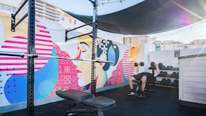 A gym with a colorful mural, weightlifting equipment, and a bench. - Live it Malaga (Málaga)
