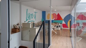 A modern office space with a glass partition, a staircase, and a colorful wall mural. - Live it Malaga (Málaga)