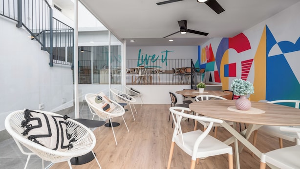 A modern dining area with a high ceiling, a staircase, and a colorful wall mural. - Live it Malaga (Málaga)