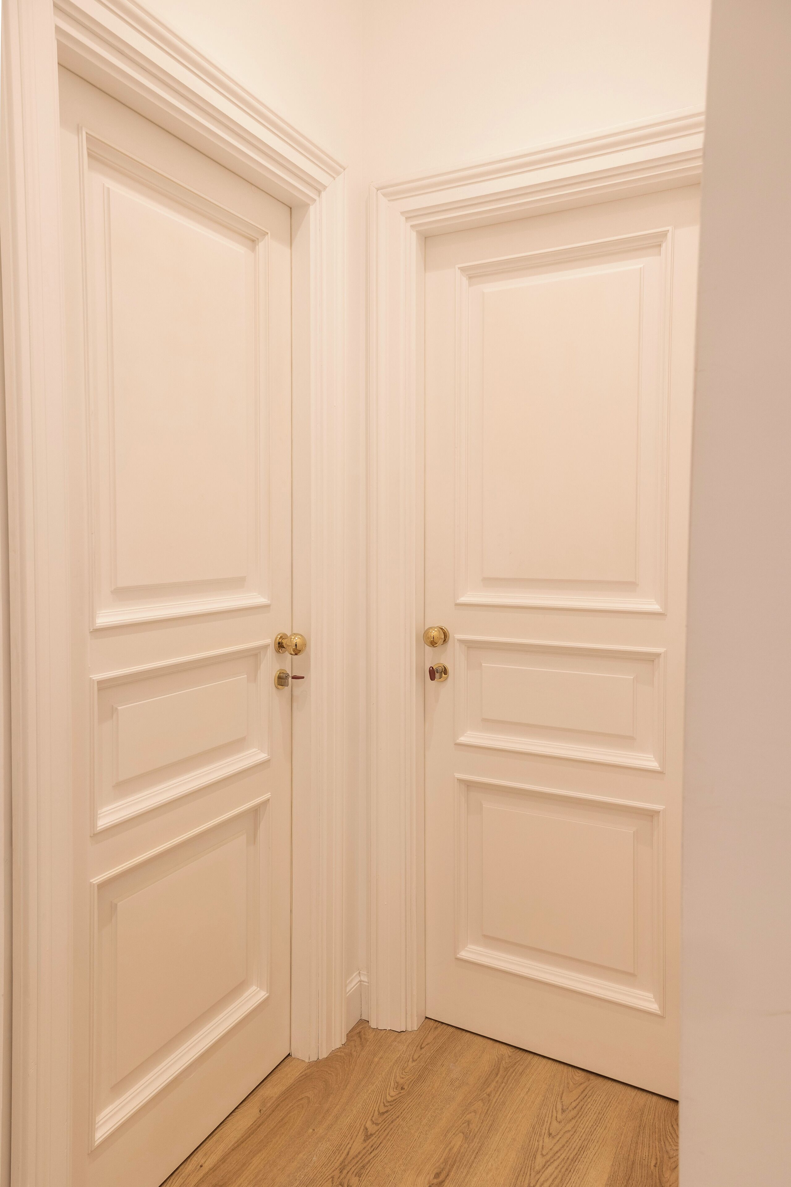 A set of white double doors with a classic design, featuring a central panel and two smaller panels on either side.