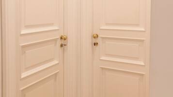 A set of white double doors with a classic design, featuring a central panel and two smaller panels on either side.