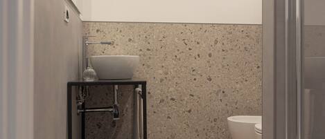 Een moderne badkamer met houten vloer, een witte wastafel, een douchecabine van glas en een handdoekrek.