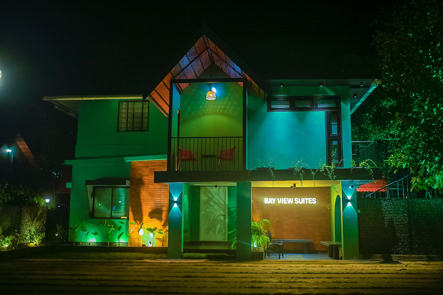 A two-story building with a prominent 'BAY VIEW SUITES' sign, a balcony with a view, and a well-lit entrance.