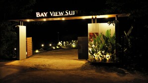 The entrance to Bay View Suites with a sign above the door, a pathway leading to the entrance, and some plants on either side. - Bay View Suites Vythiri (Vythiri)