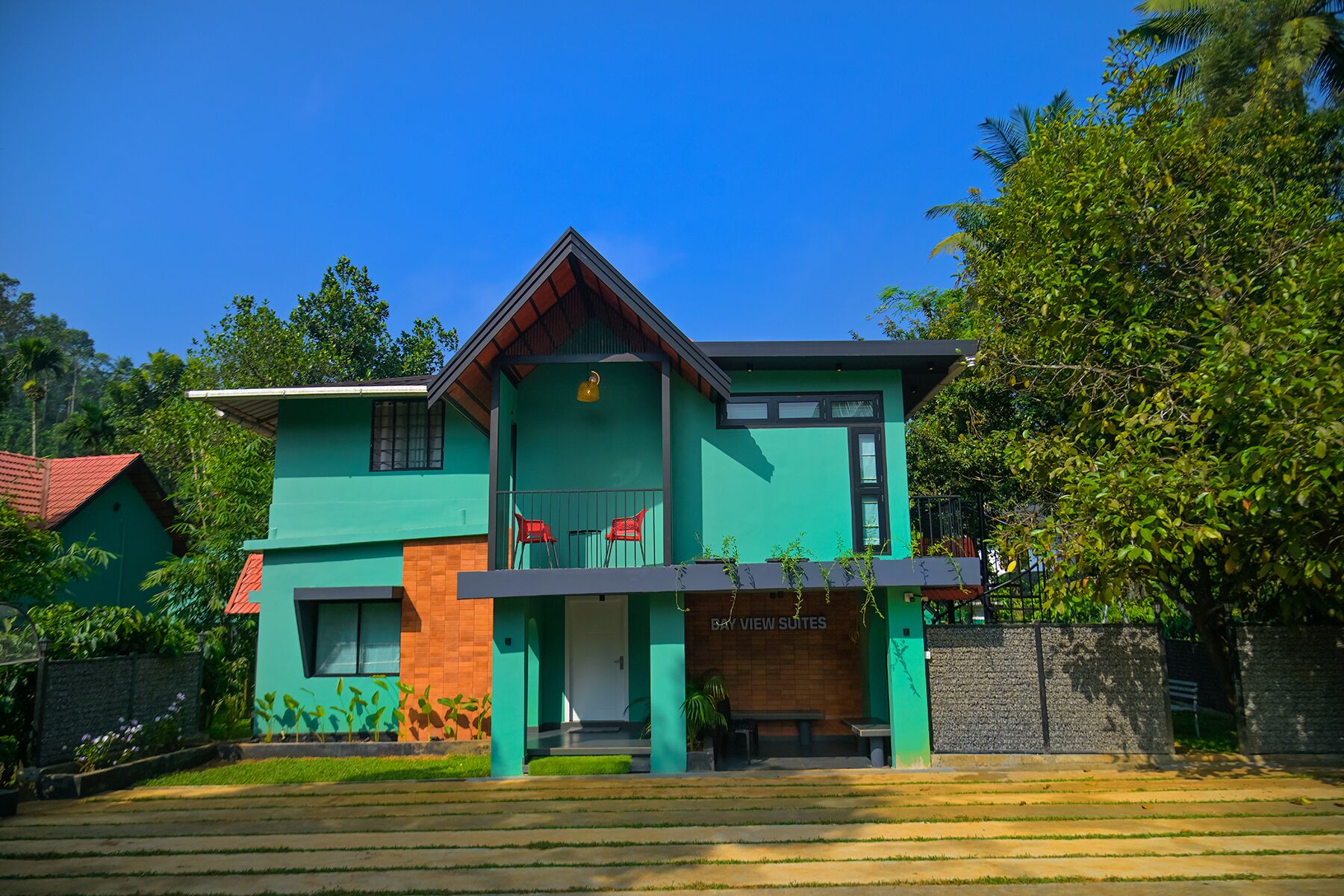 A modern two-story building with a green and orange facade, a visible entrance, and a sign reading "BAY VIEW SUITES".