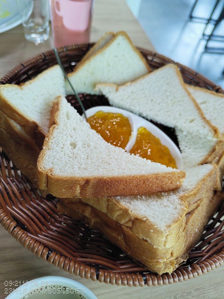 A wicker basket containing several slices of white bread with a spread of orange jam.