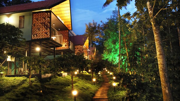 A pathway leading to a building with a red roof and a balcony with a patterned wall. - Bay View Suites Vythiri (Vythiri)