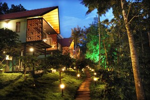 A pathway leading to a building with a red roof and a balcony with a patterned wall. - Bay View Suites Vythiri (Vythiri)