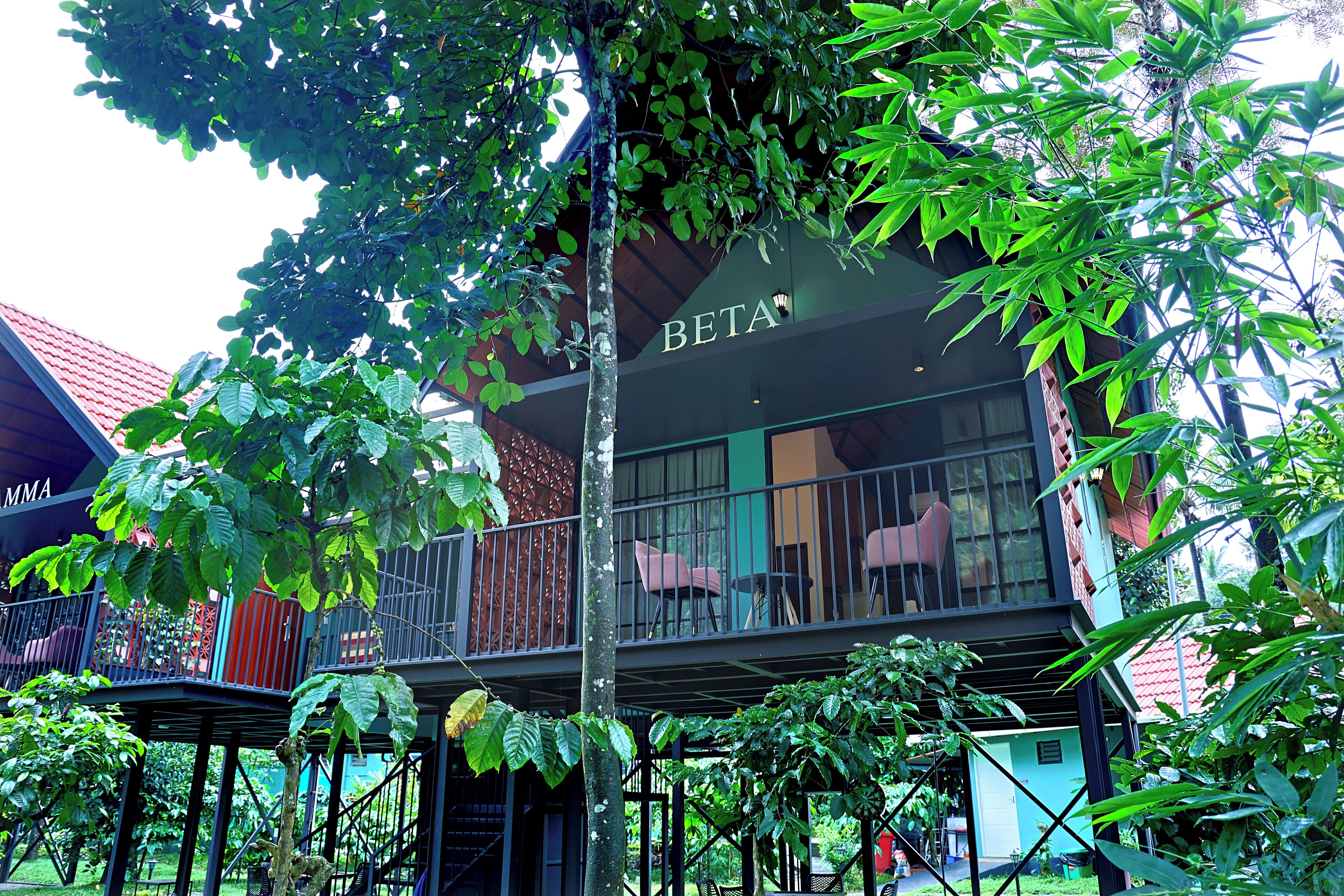 A building with a balcony and outdoor seating area, surrounded by lush greenery.