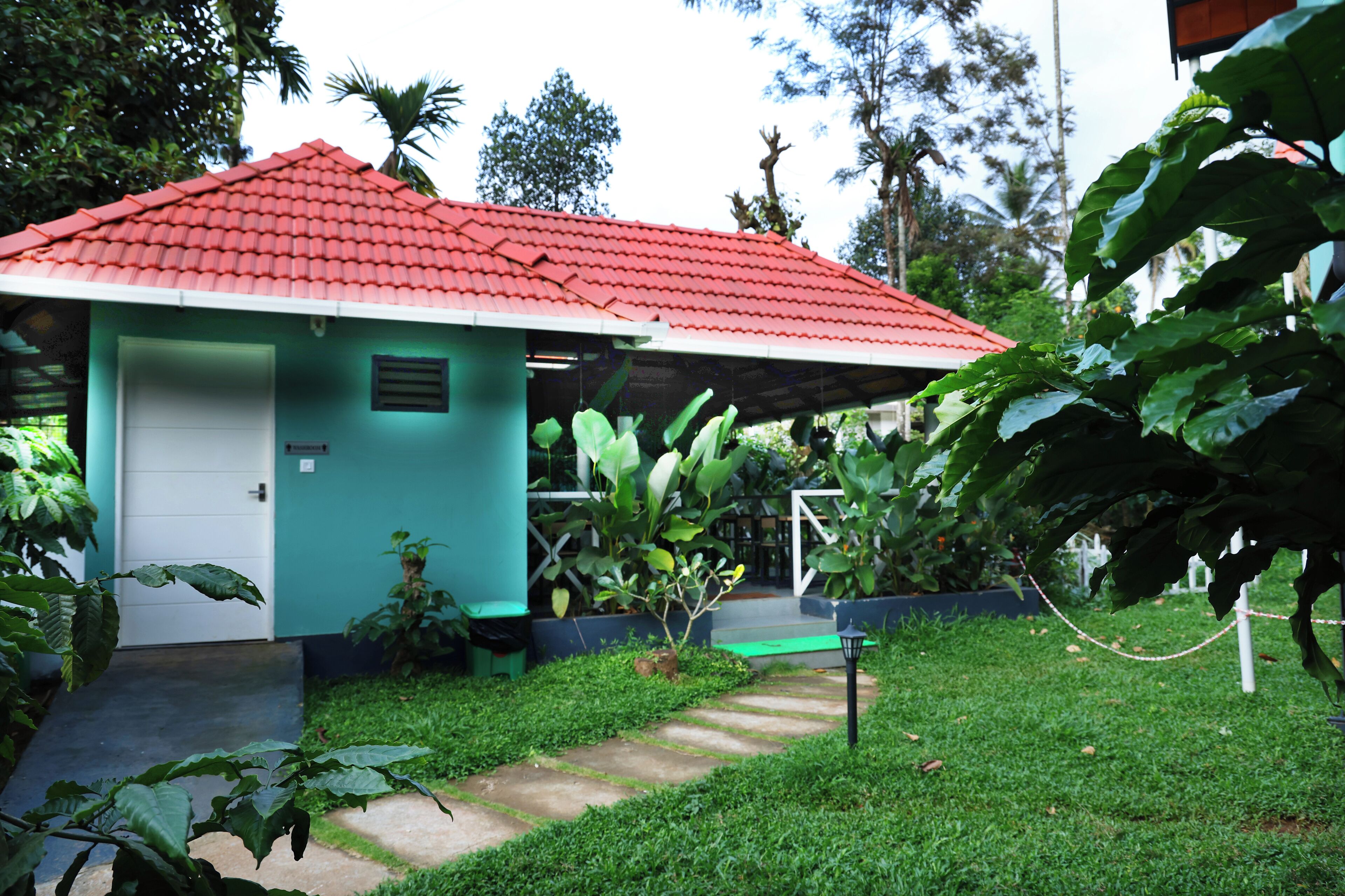 A small, single-story building with a red-tiled roof and a green exterior.