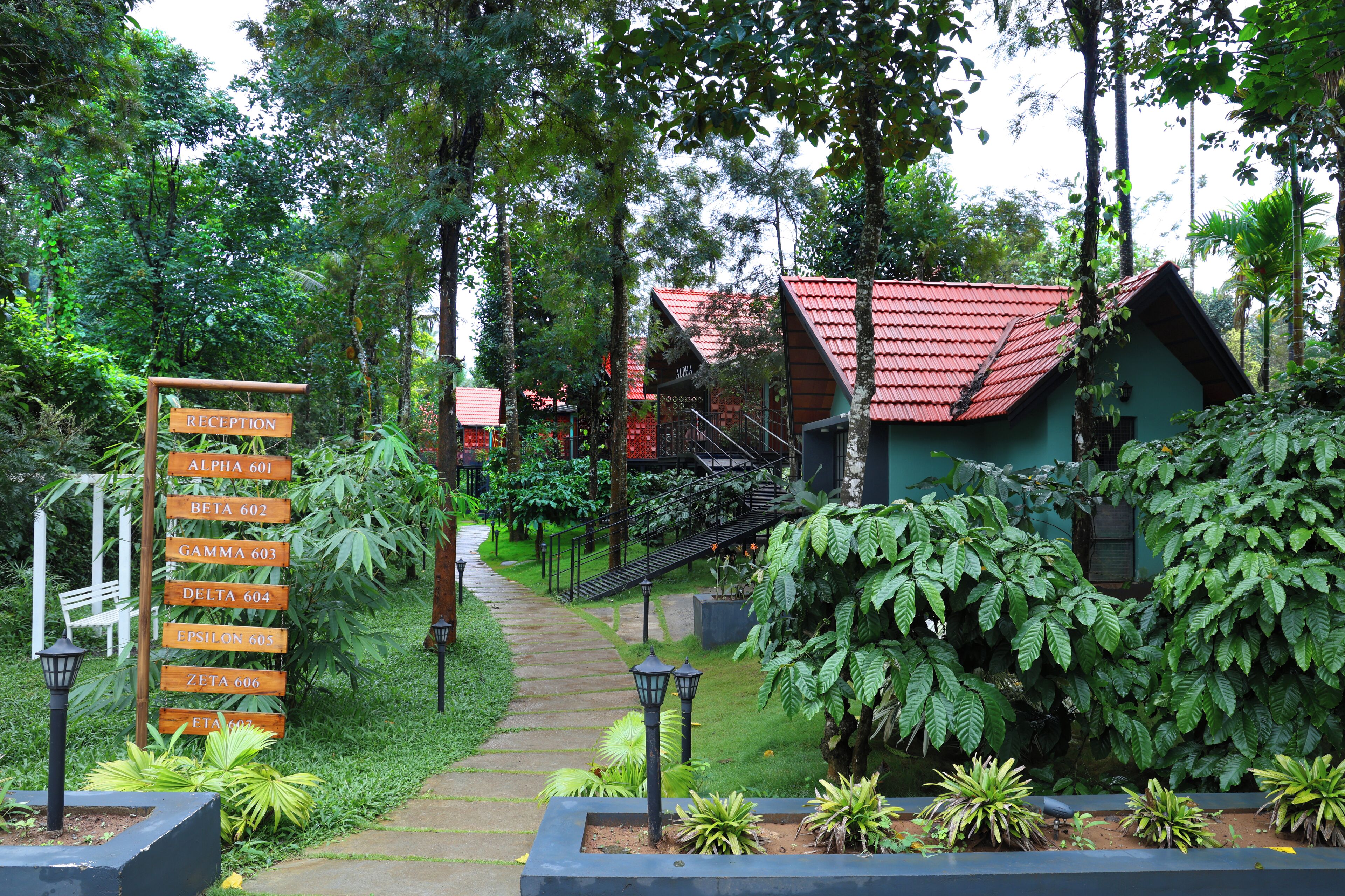 A reception area with a signpost indicating room numbers and a pathway leading to a building with a red roof.