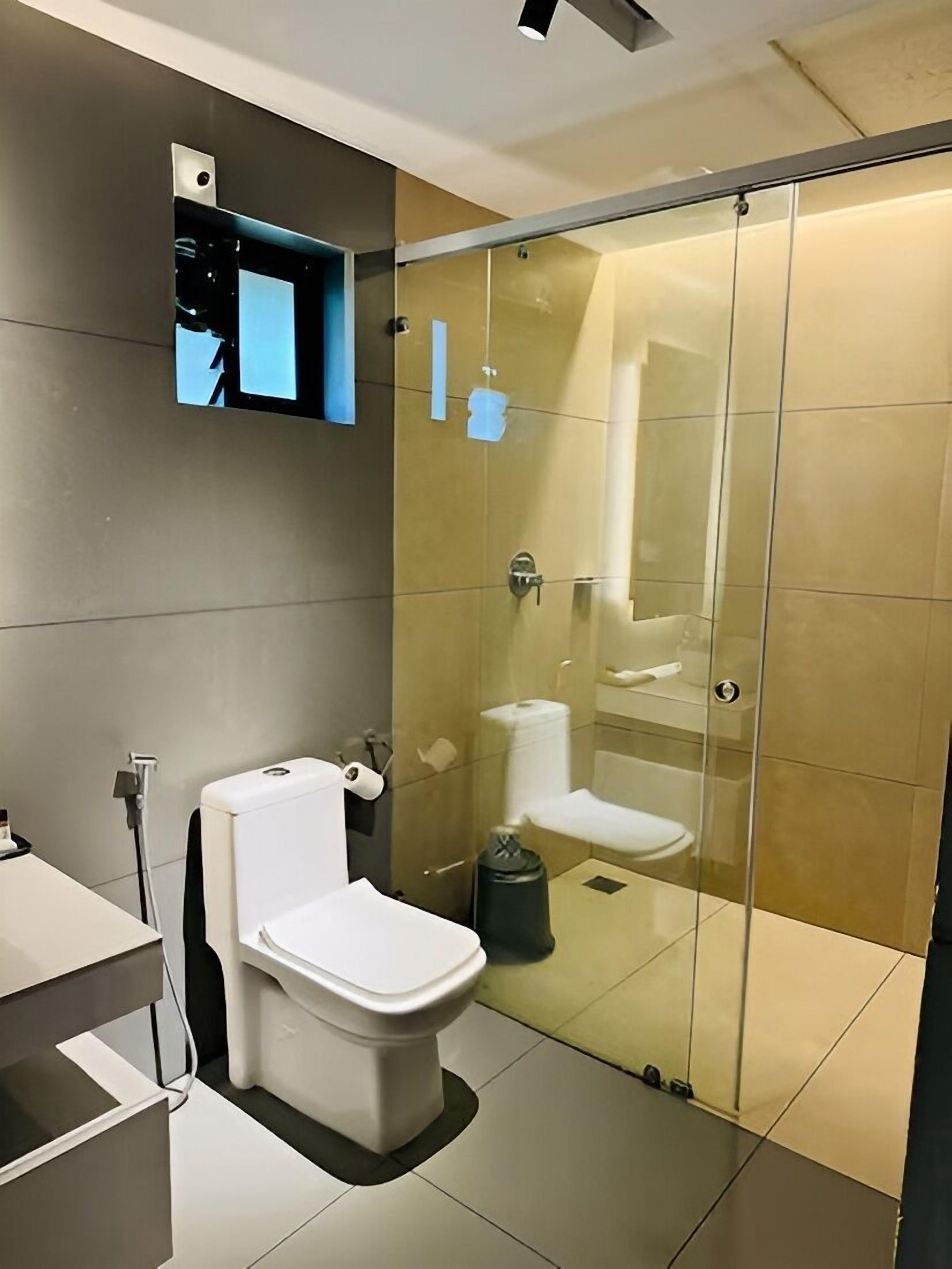 A modern bathroom with a glass-enclosed shower, a white toilet, and a sink.