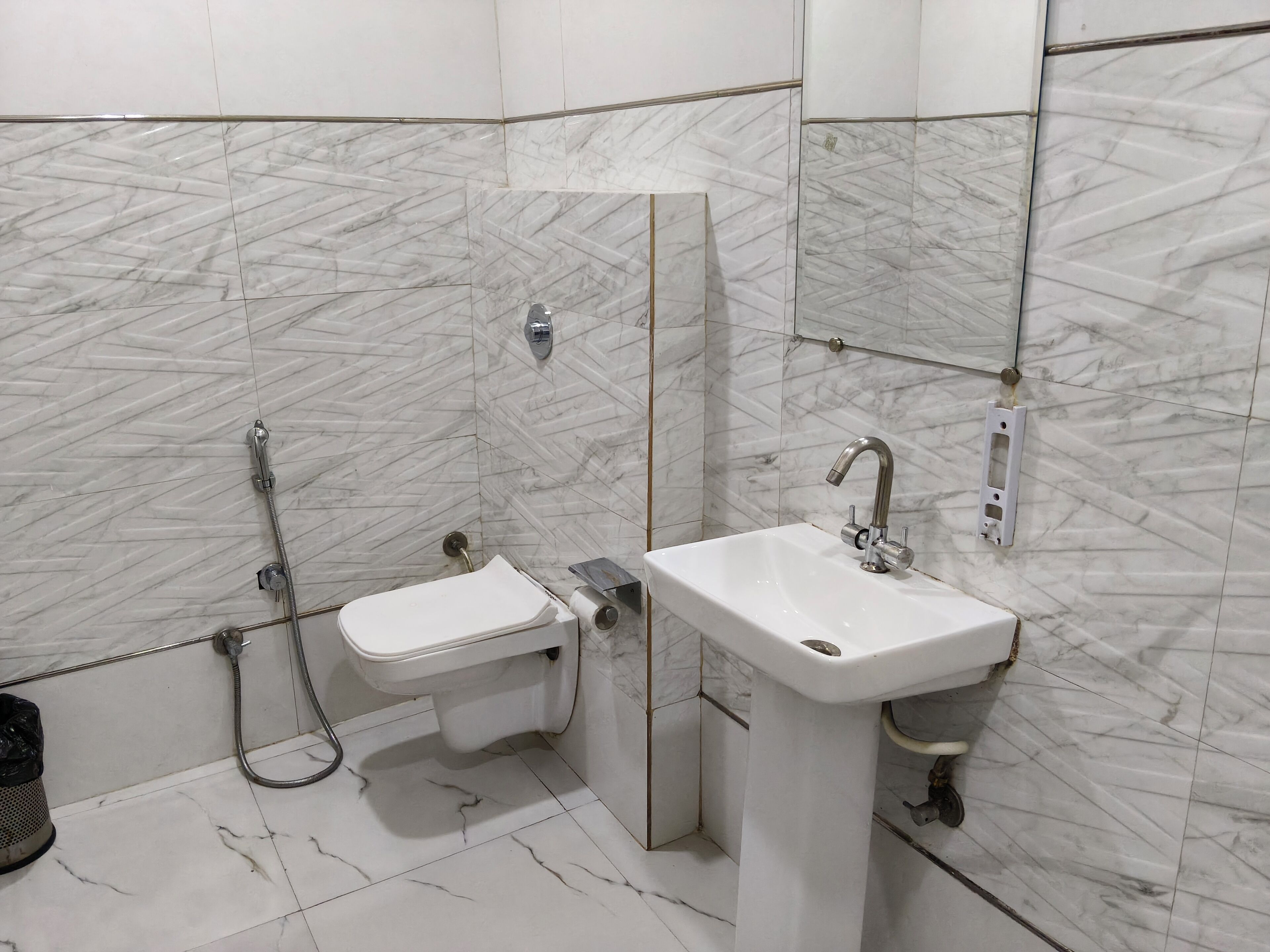 Un bagno moderno con WC, bidet e lavandino, tutti dotati di accessori cromati.