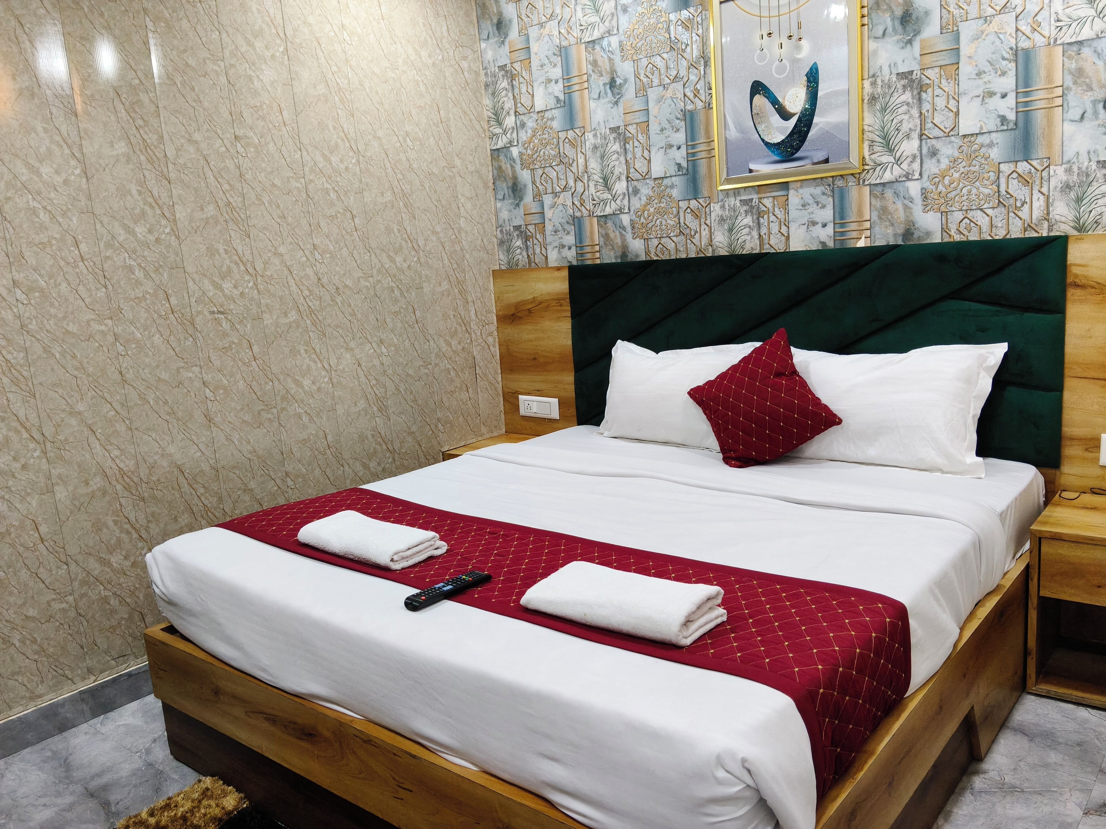 Un lit bien fait, avec des draps blancs, une couverture rouge matelassée et deux serviettes blanches.