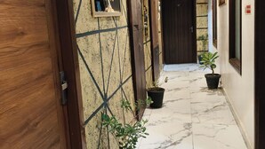 A hallway with wooden doors numbered 05 and 07, potted plants, and a marble floor. - Hotel Bella Vista Inn (Amritsar)