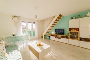Uma sala de estar moderna com escada, área de jantar e televisão.