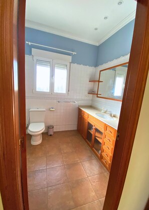 Un baño con inodoro, lavamanos y espejo.
