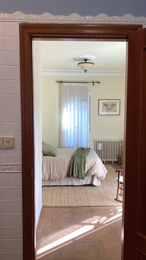 Un dormitorio con cama, radiador, ventana con cortinas y ventilador de techo.