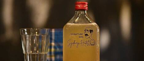 A bottle of signature sips with a red cap and a glass beside it.