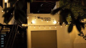 A building with a closed garage door, a staircase, and string lights. - Snooze Station by Sydney Galle (Galle)