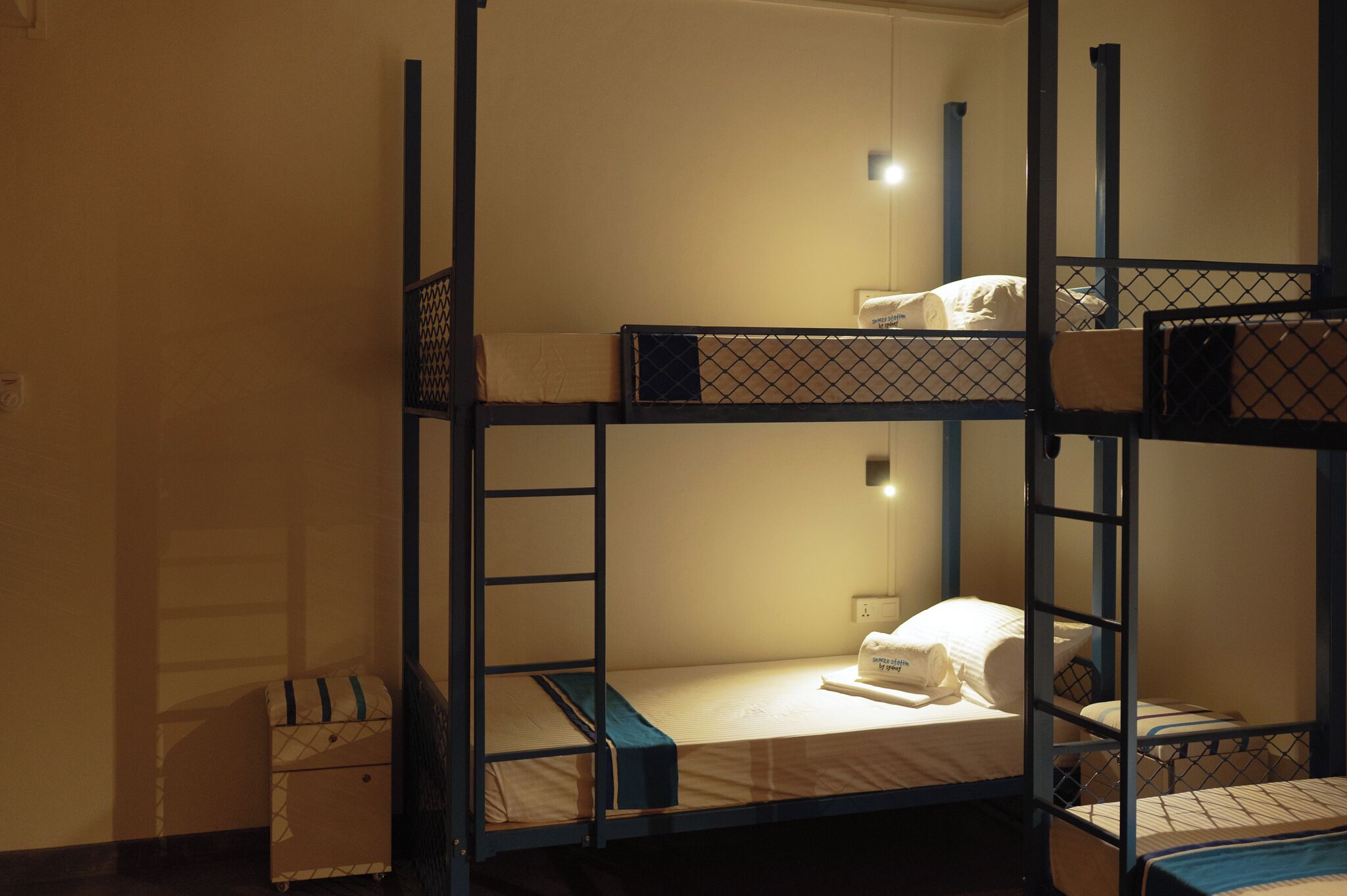 A bunk bed room with a small bedside table and a power outlet.