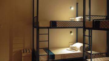 A bunk bed room with a small bedside table and a power outlet.