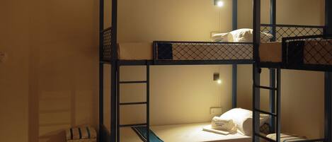 A bunk bed room with a small bedside table and a power outlet.