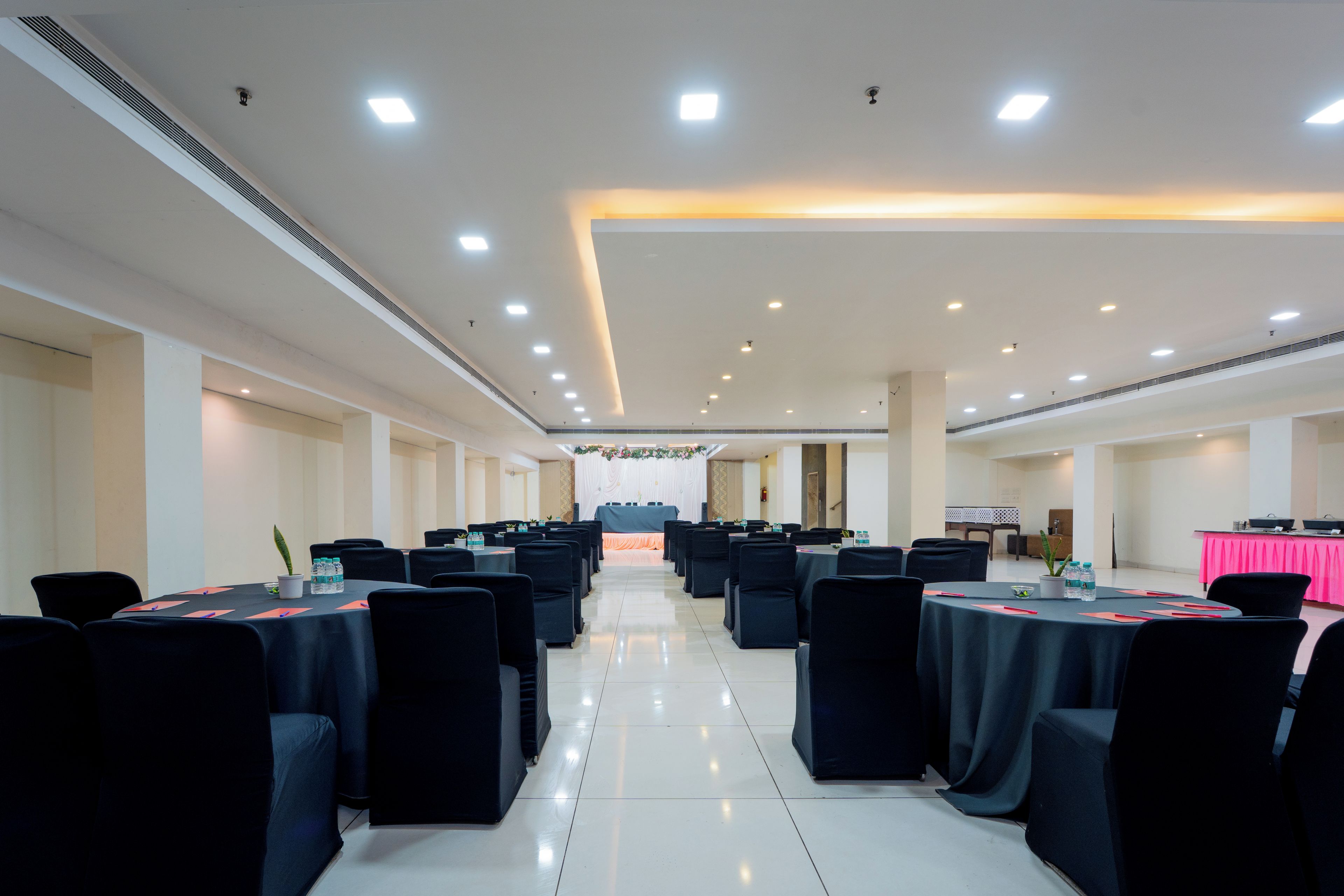A conference room with multiple tables and chairs, equipped with water bottles and nameplates.