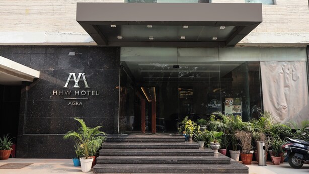 The entrance of HHW Hotel with a modern facade, steps leading up to the entrance, and potted plants in front. - HHW Hotel- Agra (Agra)