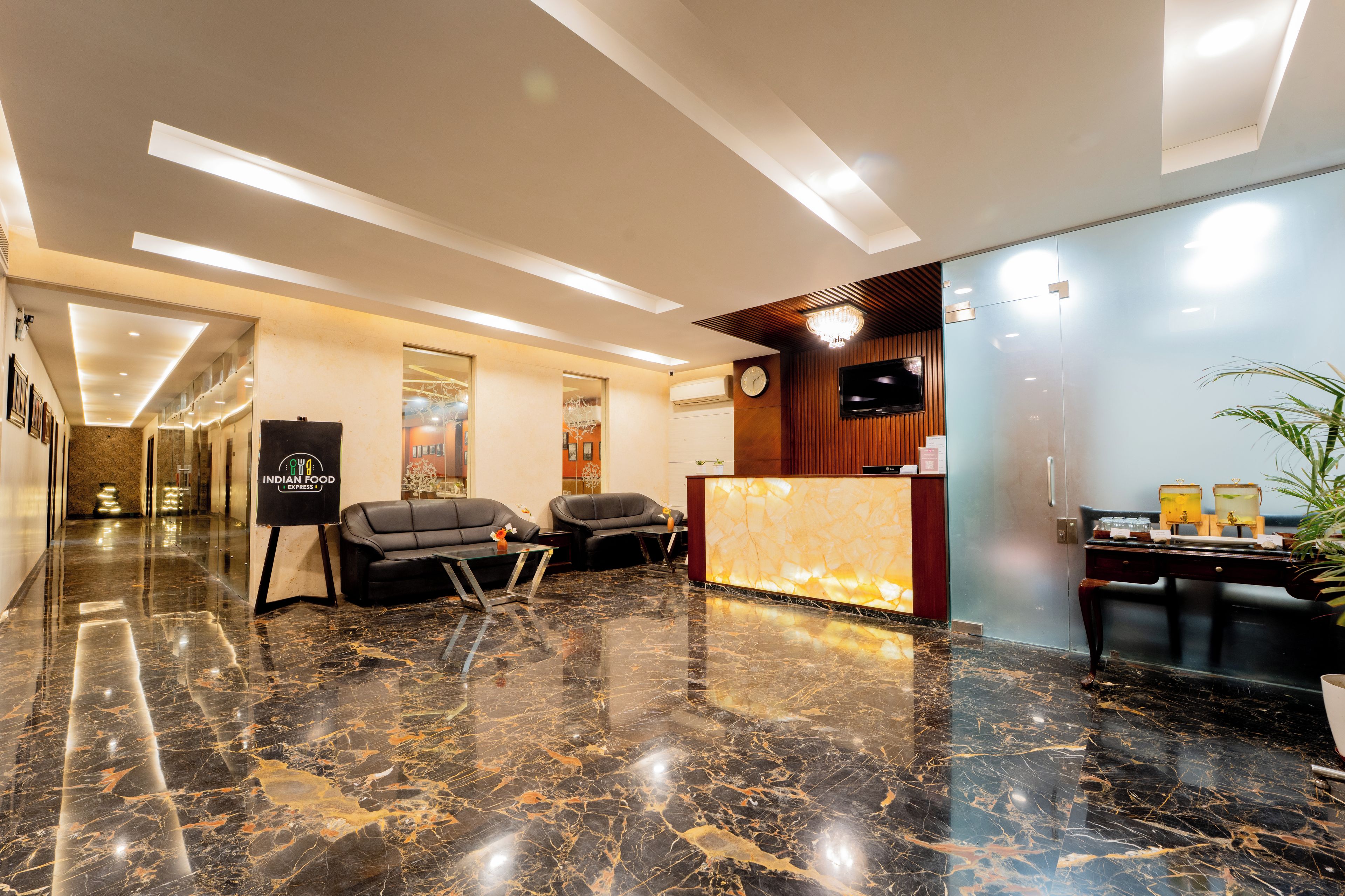 A hotel lobby with a reception desk, seating area, and a clock on the wall.