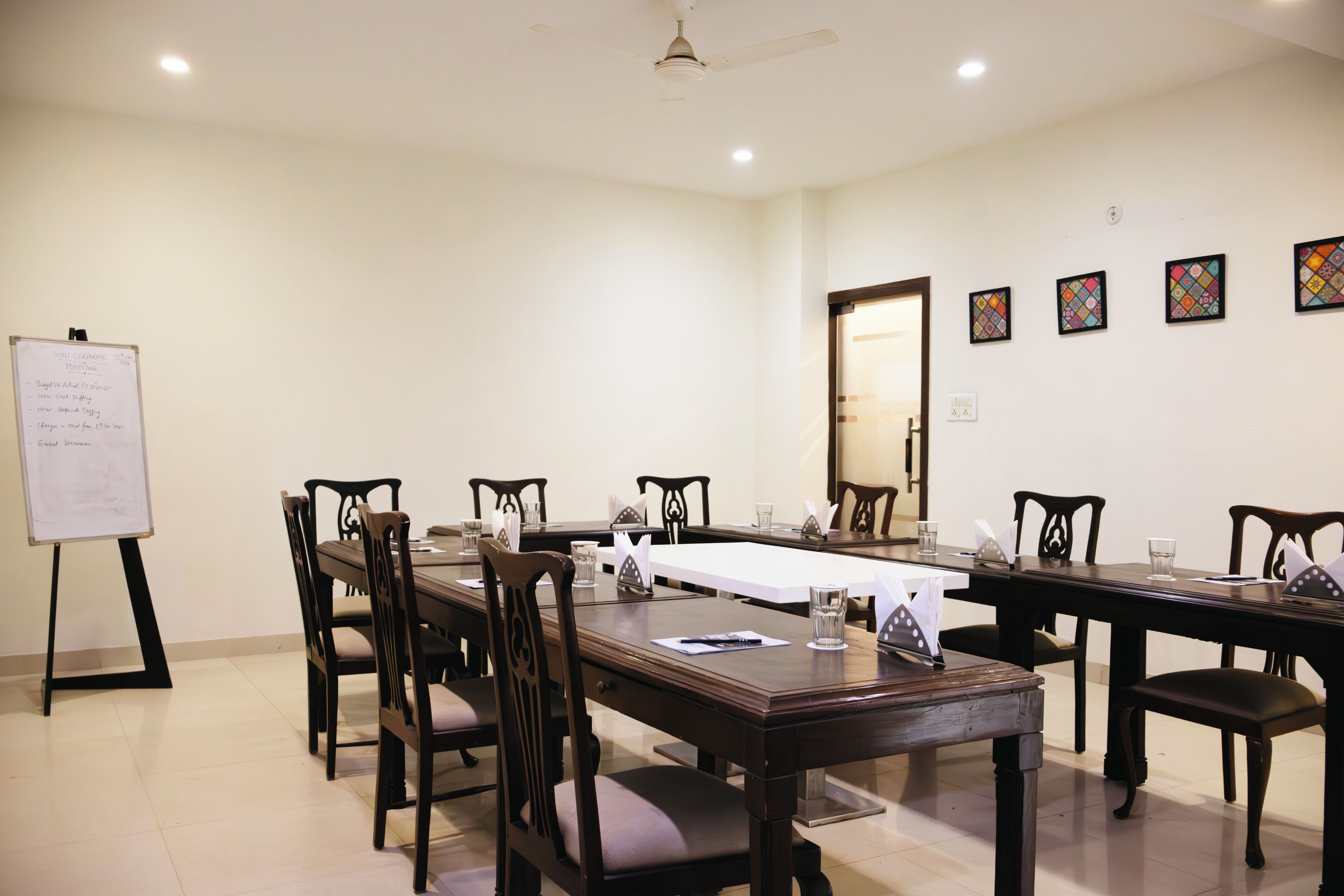 A conference room with a long table, chairs, a whiteboard, and framed pictures on the wall.