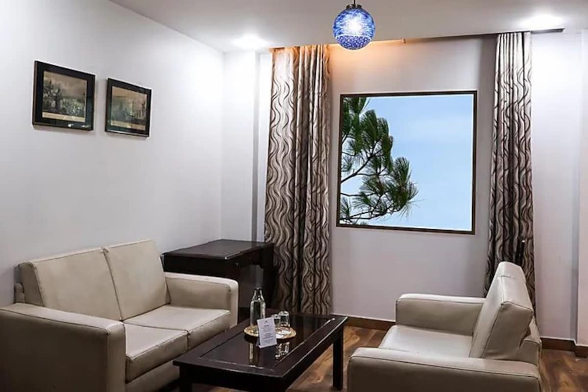 A modern living room with two sofas, a coffee table, and a large window with a view of trees.