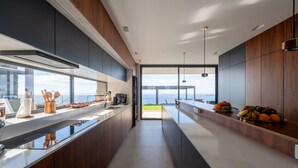 A modern kitchen with a long island, dark wood cabinets, and a view to the outside.