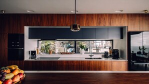 A modern kitchen with dark wood cabinets, a central island, and a view of the outdoors.