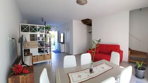 Un salon moderne comprenant un coin repas, un canapé rouge et un meuble en bois agrémenté de plantes.