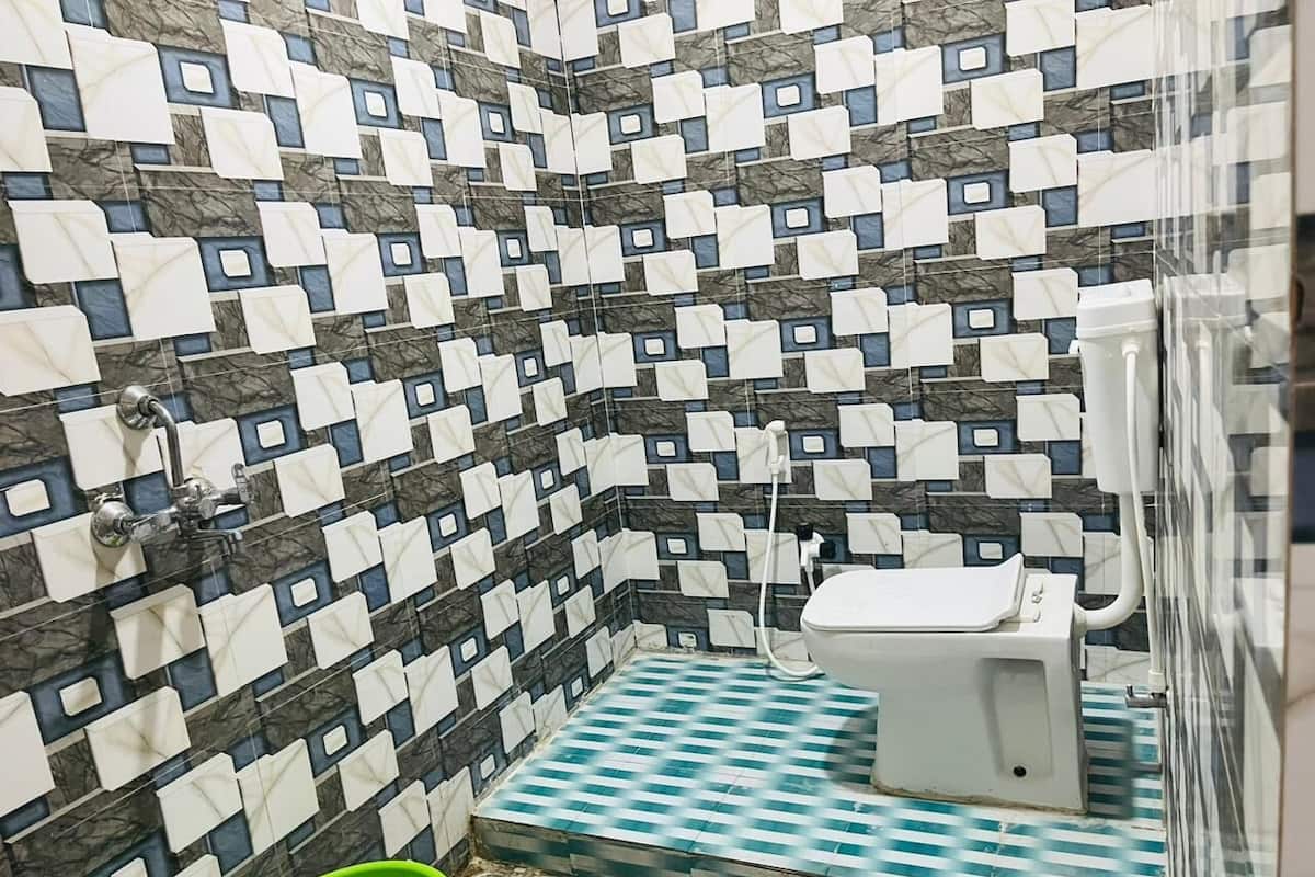 A small bathroom with a tiled floor, a toilet, and a green bucket.