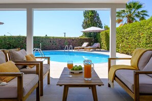 Ein Poolbereich mit Liegestühlen, einem Tisch mit Getränken und freiem Blick auf den Pool.