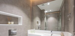 Een moderne badkamer met een grote spiegel, twee wasbakken en een douchehoek.