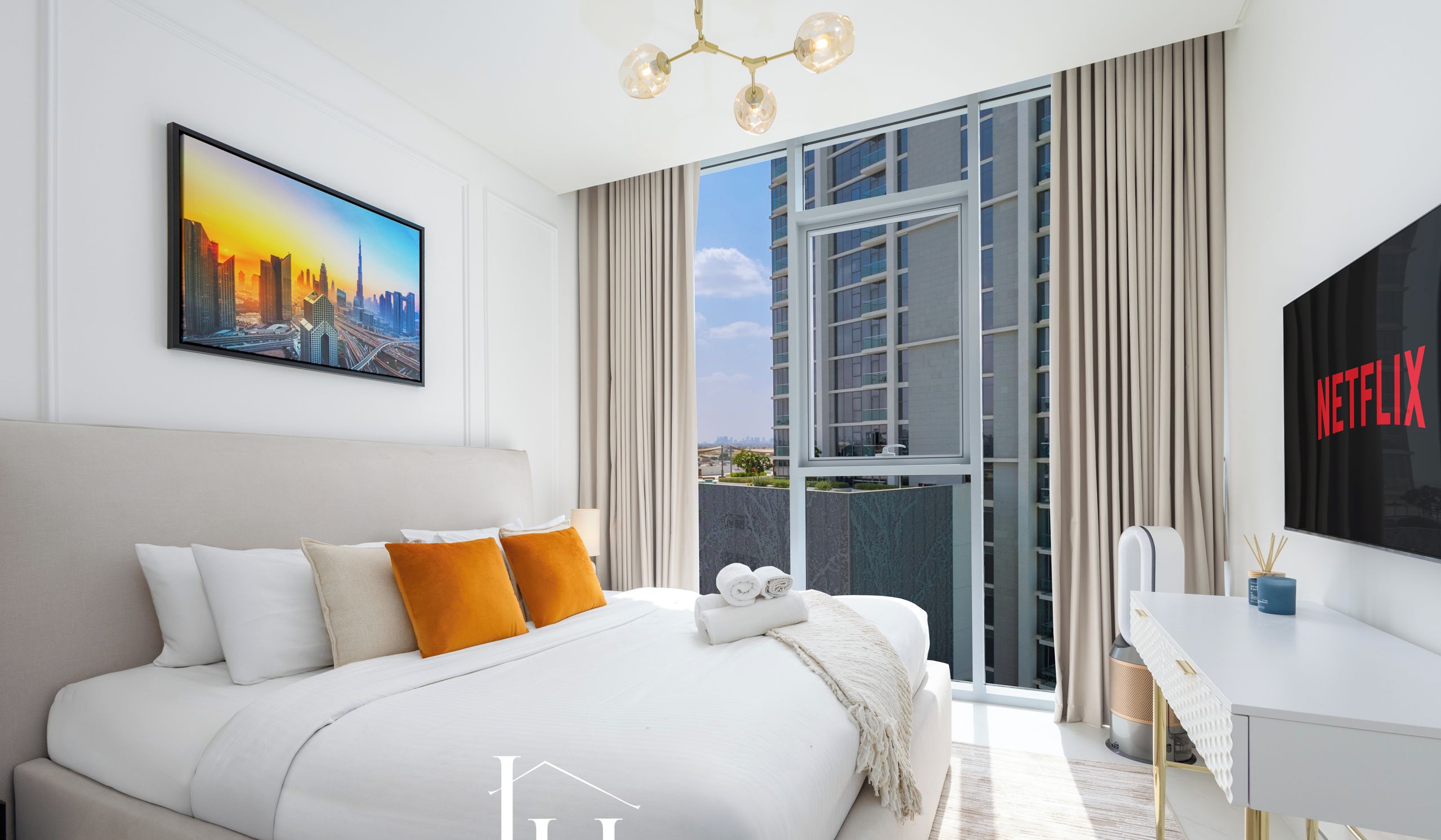 Una habitación de hotel moderna con una cama grande, un cuadro de un paisaje urbano, un balcón con cortinas, un escritorio con el logotipo de Netflix y vistas a edificios.