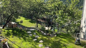 A garden with a stone pathway, trees, and a view of distant mountains.