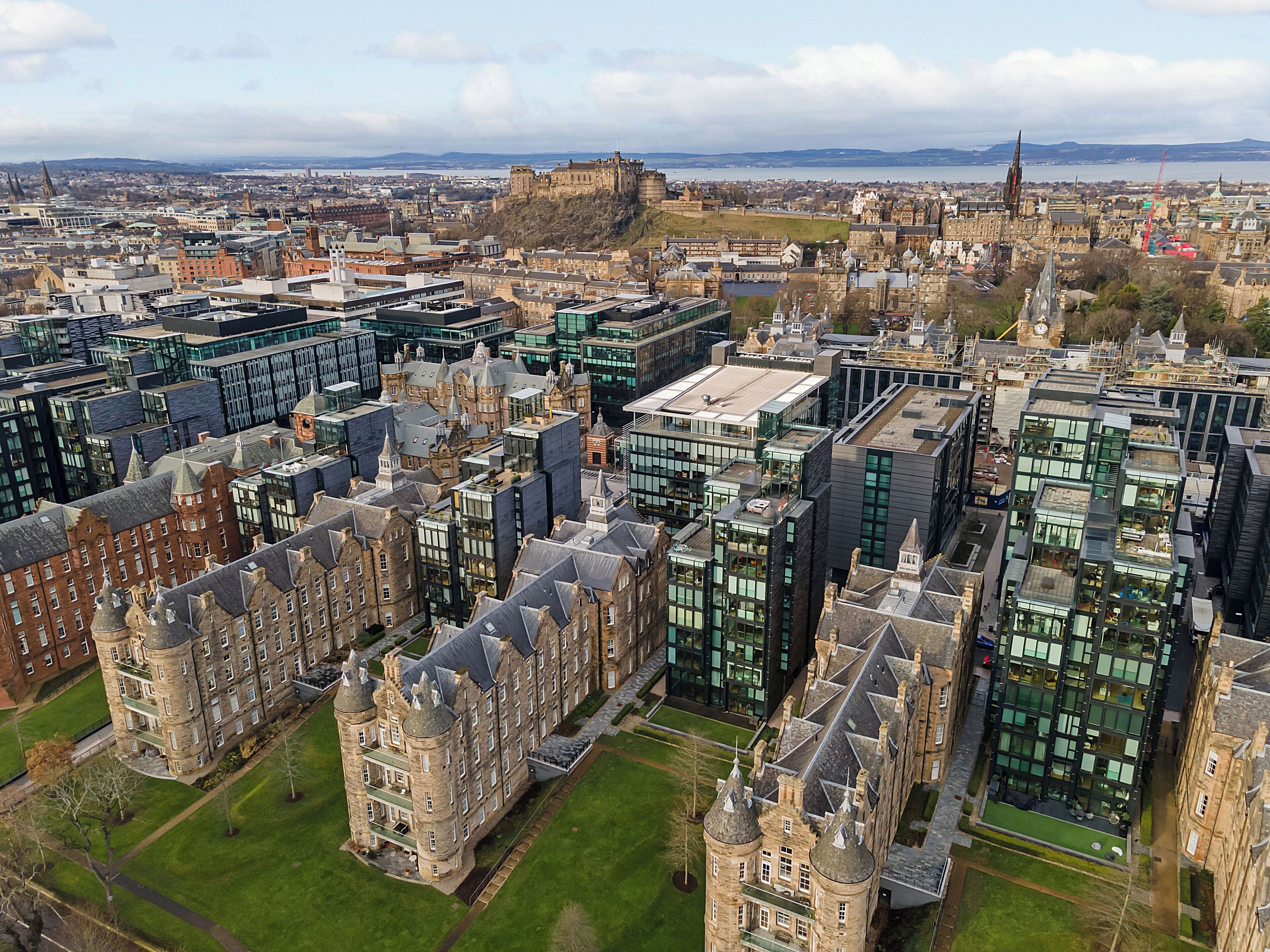 A historic building with multiple towers and a central courtyard, surrounded by modern buildings.