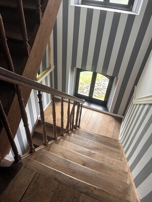 Staircase leads to a landing with a window and wooden floor.
