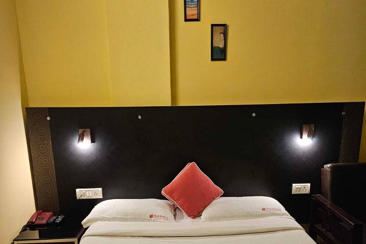 A hotel room with a bed, a nightstand, a telephone, and two wall-mounted lights.
