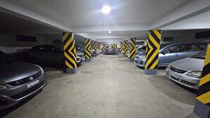 Eine mehrgeschossige Parkgarage mit in Reih und Glied geparkten Autos, säulenförmigen Pfeilmarkierungen und Deckenbeleuchtung.