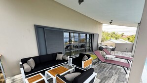 Ein moderner Außenbereich mit einer Sitzecke, einer Couch und Sesseln, einem Esstisch und Blick ins Freie.