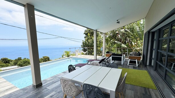 Eine moderne Außenpatio mit Pool, Sitzbereich und Meerblick.