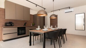 A modern kitchen with built-in appliances, a dining table set for four, and pendant lighting. - AdeLis Residence (Piran)