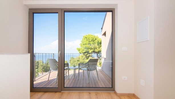A room with a sliding glass door leading to an outdoor deck with a table and chairs. - AdeLis Residence (Piran)