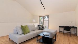 A modern living room with a grey sofa, a black coffee table, and a desk with a chair. - AdeLis Residence (Piran)
